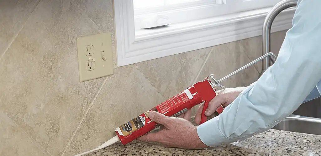 Handyman applying caulk along a kitchen backsplash and countertop seam in Savannah, GA