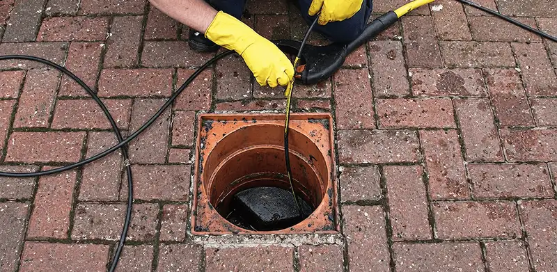 Drain cleaning technician using a drain snake to clear a clogged drain in Savannah, GA