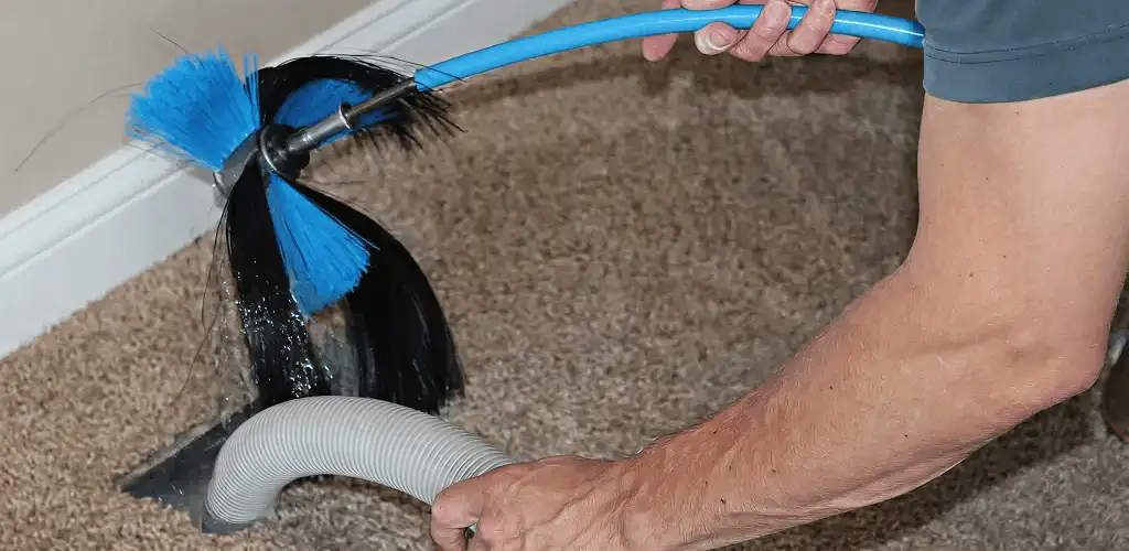 Dryer vent cleaning technician brushing lint from a vent line in Savannah, GA