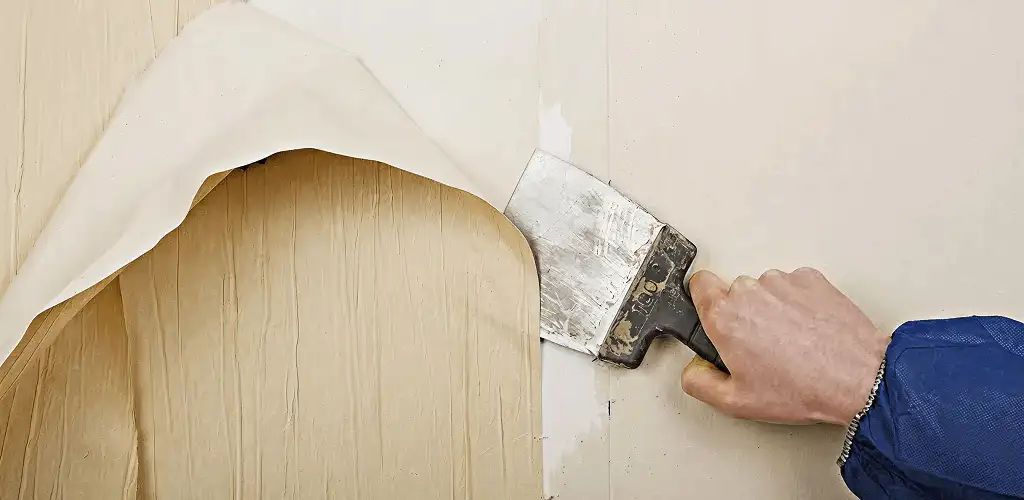 Handyman removing wallpaper with a scraper for wall preparation in Savannah, GA