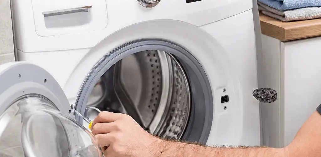 Handyman repairing a front-load washing machine and inspecting the drum in Savannah, GA