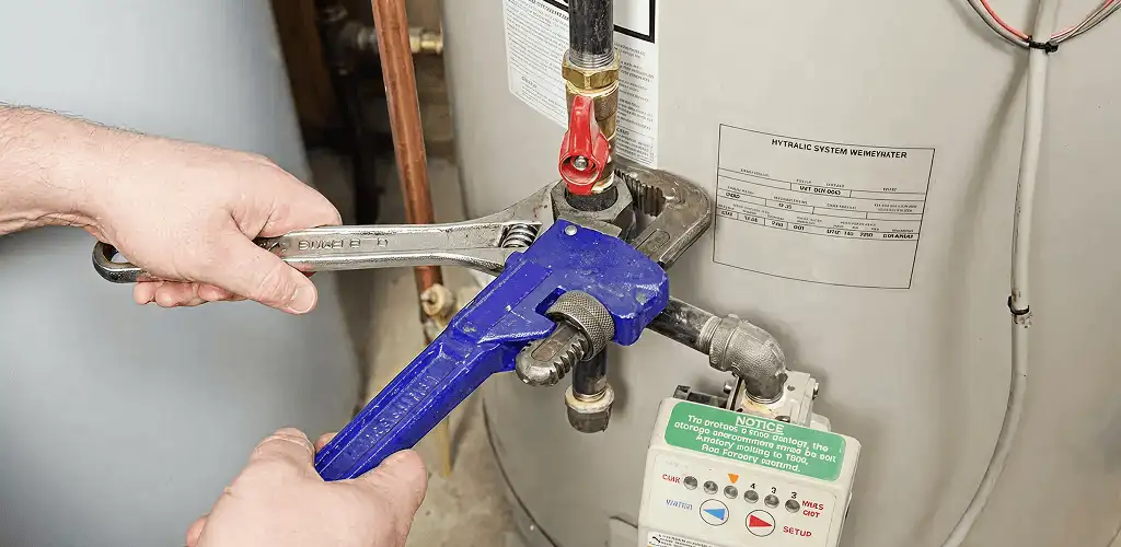 Water heater repair technician tightening the shutoff valve and supply line in Savannah, GA